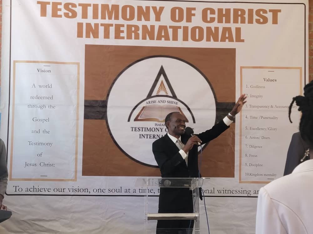 A minister preaching beside the TCI vision and values banner