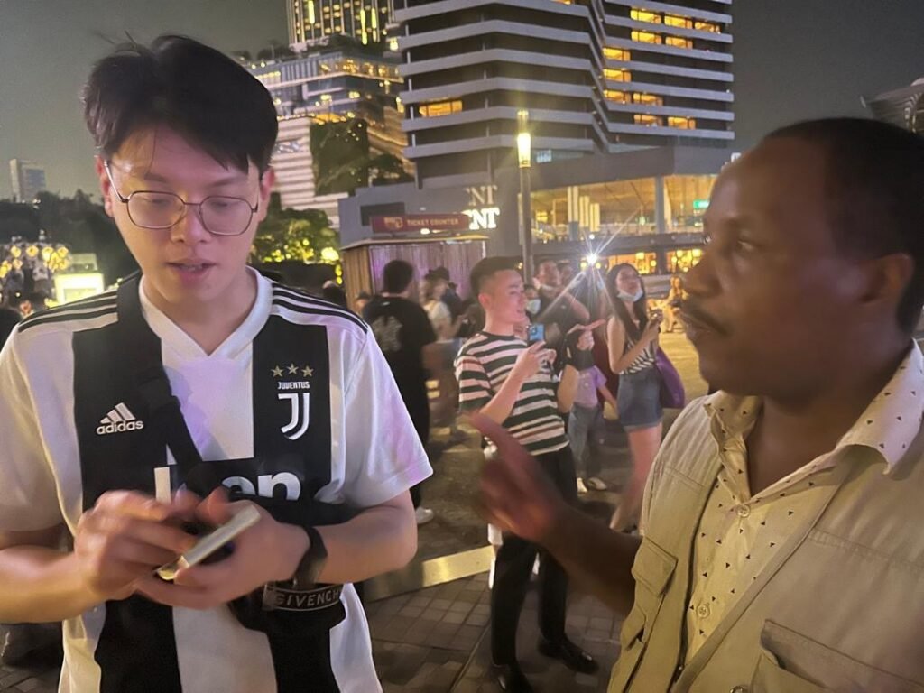 A TCI minister talking with a young man on a busy city street during the Global Tour