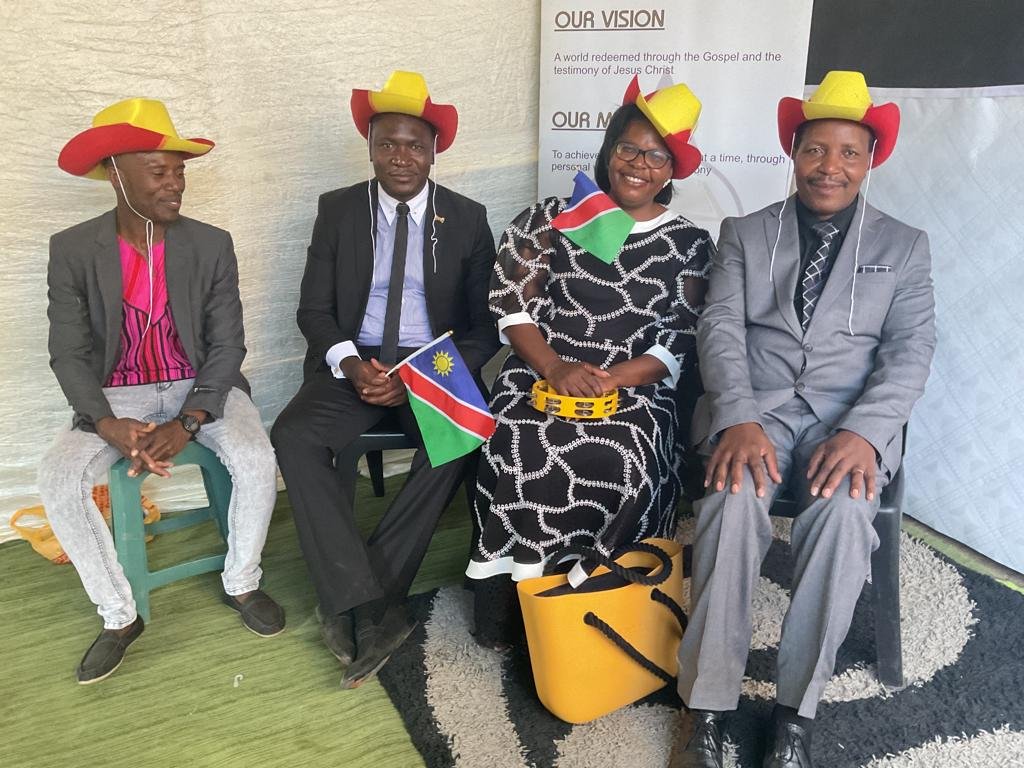 TCI Namibia leaders seated together holding the national flag