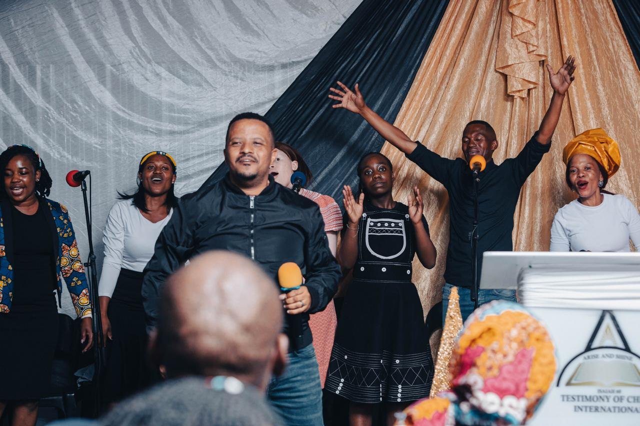 The TCI congregation worshipping joyfully with hands raised