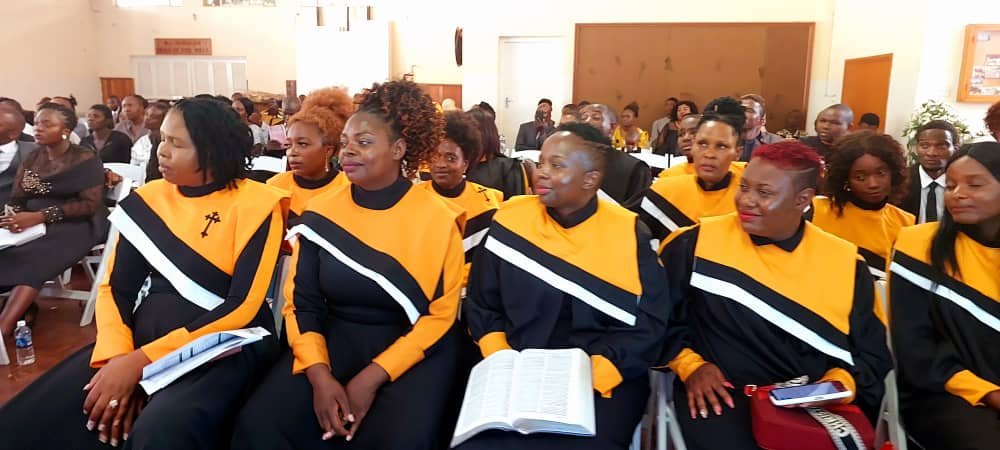 TCI women in black and gold robes at a service