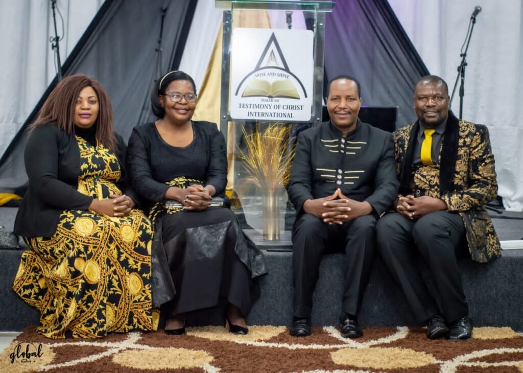 Two TCI couples seated on stage in front of the TCI emblem